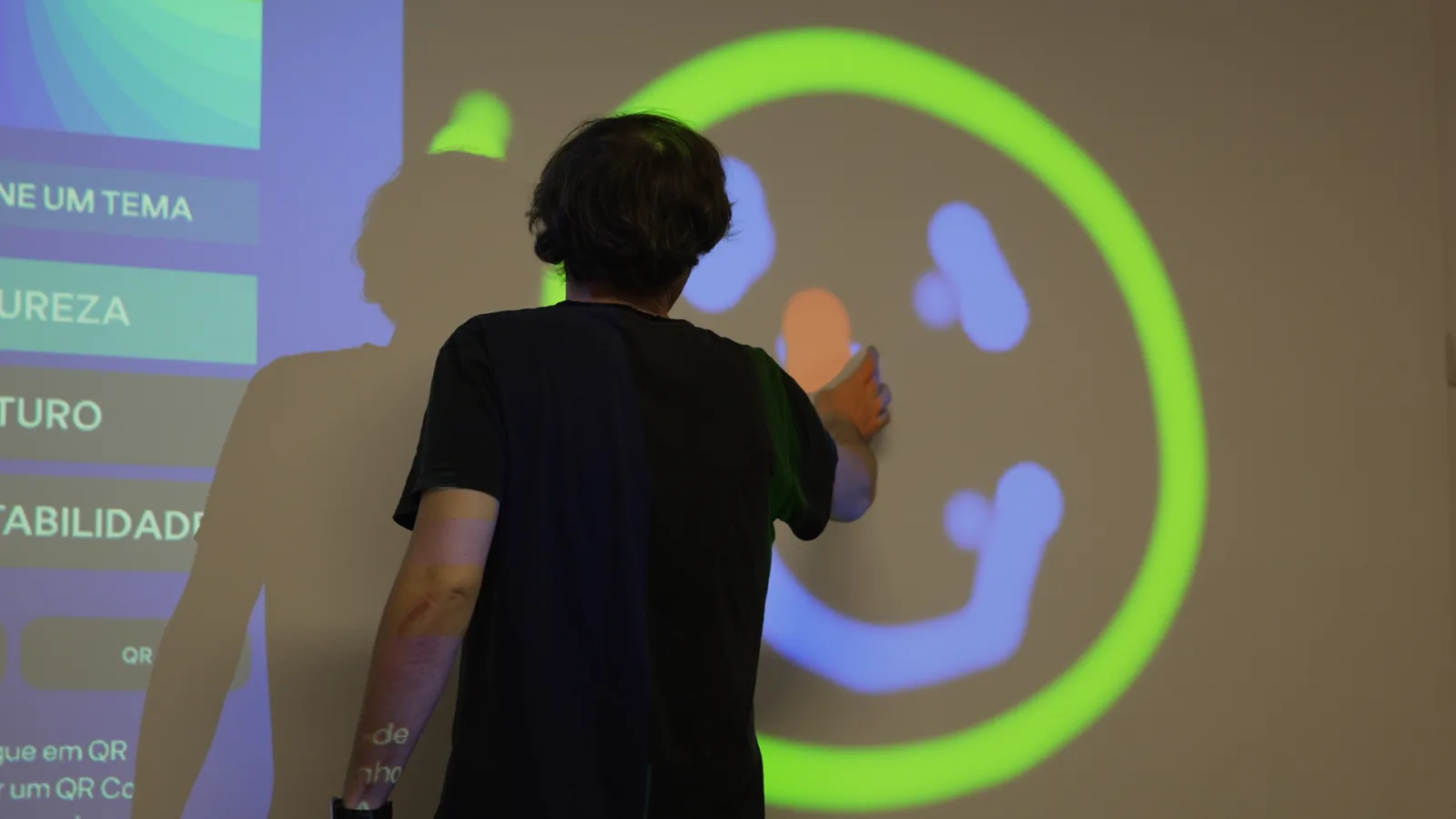 Um visitante a desenhar com a mão numa grande superfície projetada